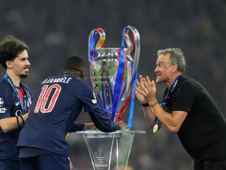 PSG's head coach Luis Enrique and players Vitinha, left, and Ousmane Dembele look at the trophy at the end of the Champions League final soccer match between Paris Saint-Germain and Inter Milan at the Allianz Arena in Munich, Germany, Saturday, May 31, 2025. (AP Photo/Luca Bruno)

- XCHAMPIONSLEAGUEX